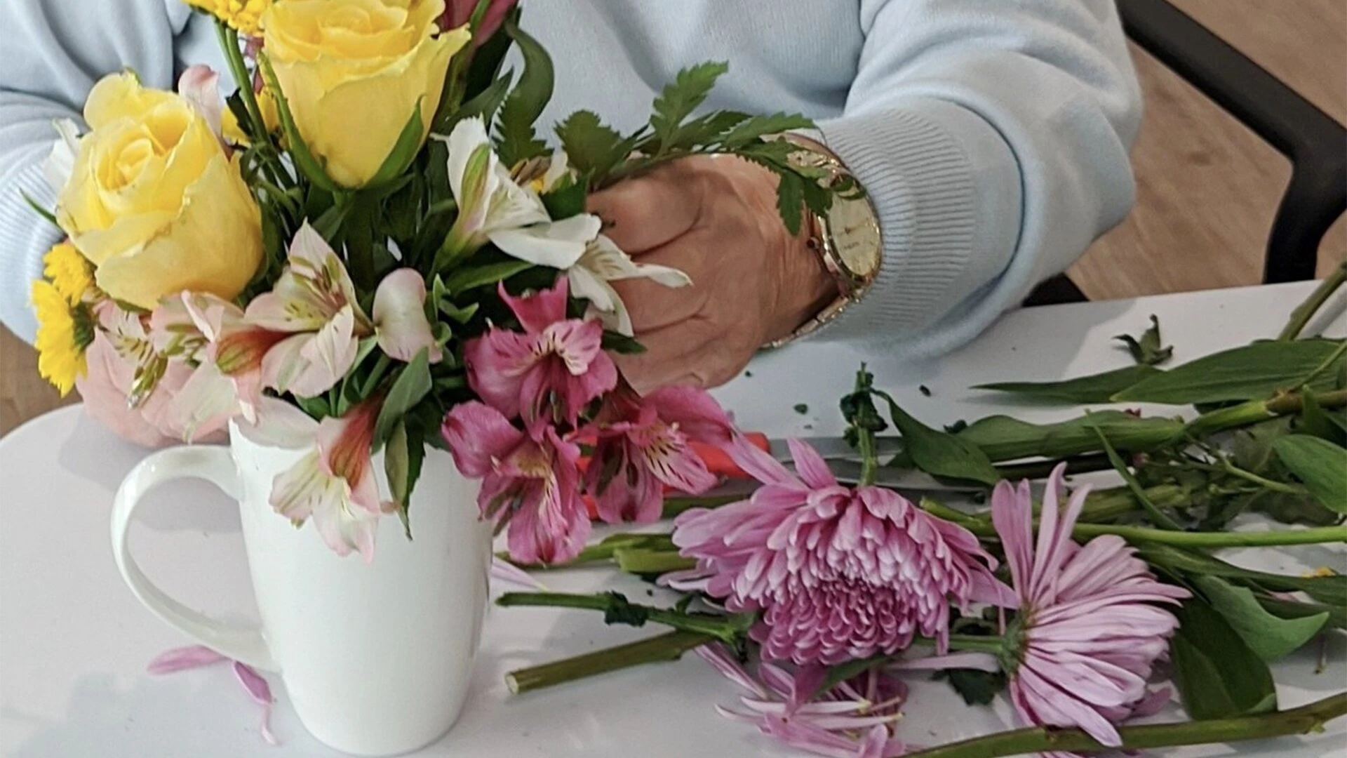 Elderly hands making flower bouquet in a cup at Hawthorne