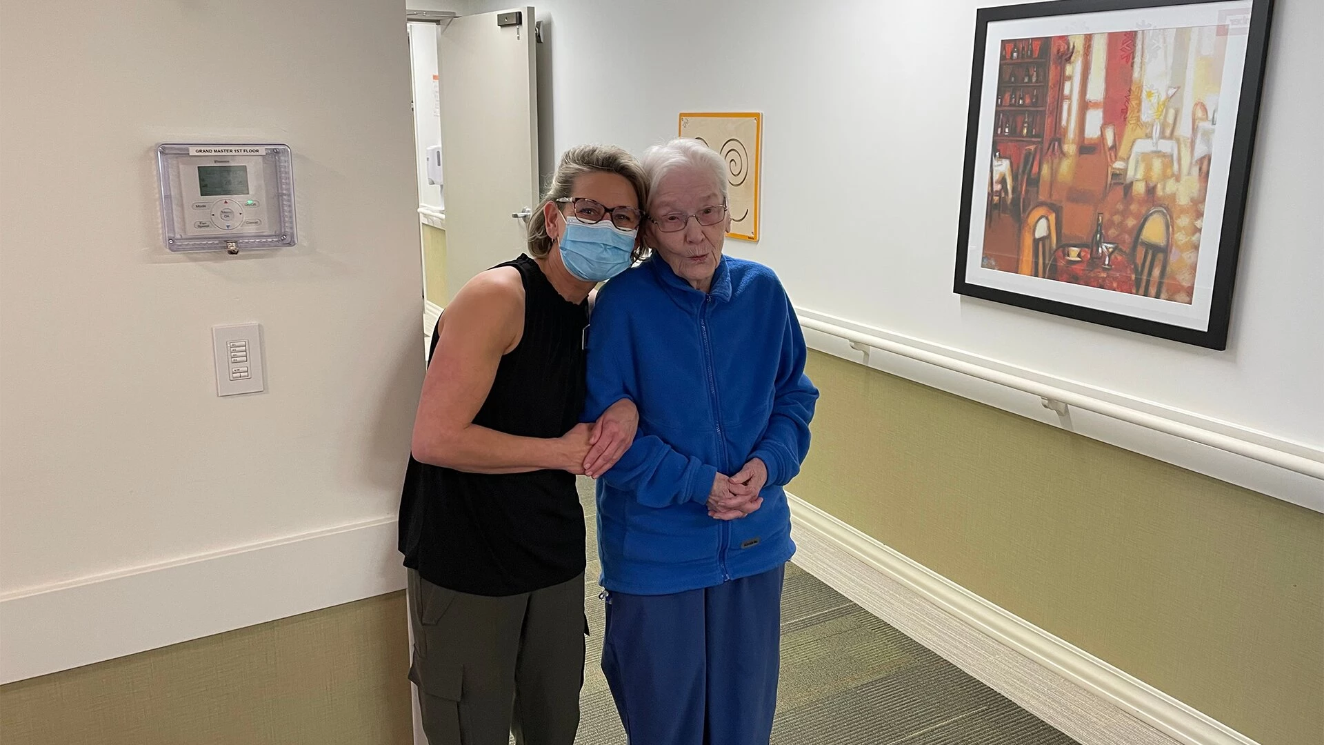 A couple of elderly women holding each other in the corridors at Hawthorne residence